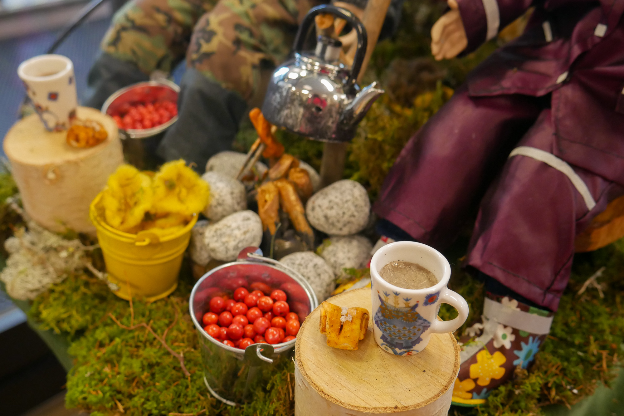 Lähikuva syksyisestä pienosmalliasetelmasta, kuvassa marja- ja sieniämpäri, kahvipannu ja -kupit sekä korvapuusteja.